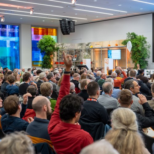 Die Teilnehmenden des Herbstforums Altbau schauen in Richtung Bühne. Dort macht sich Moderatorin Natasha Walker ein Stimmungsbild per Handzeichen.