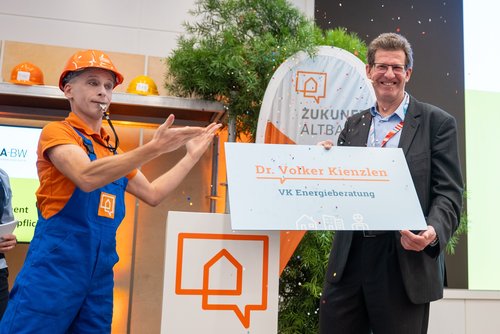 Das Foto zeigt Dr. Volker Kienzlen, der ein Schild überreicht bekommt. 