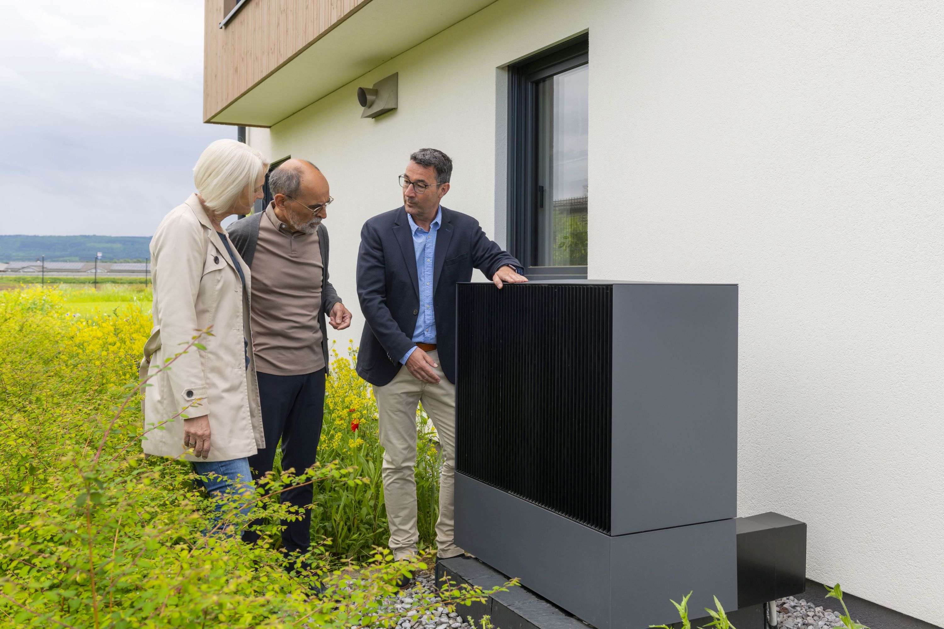 Drei Personen stehen neben einer Wärmepumpe