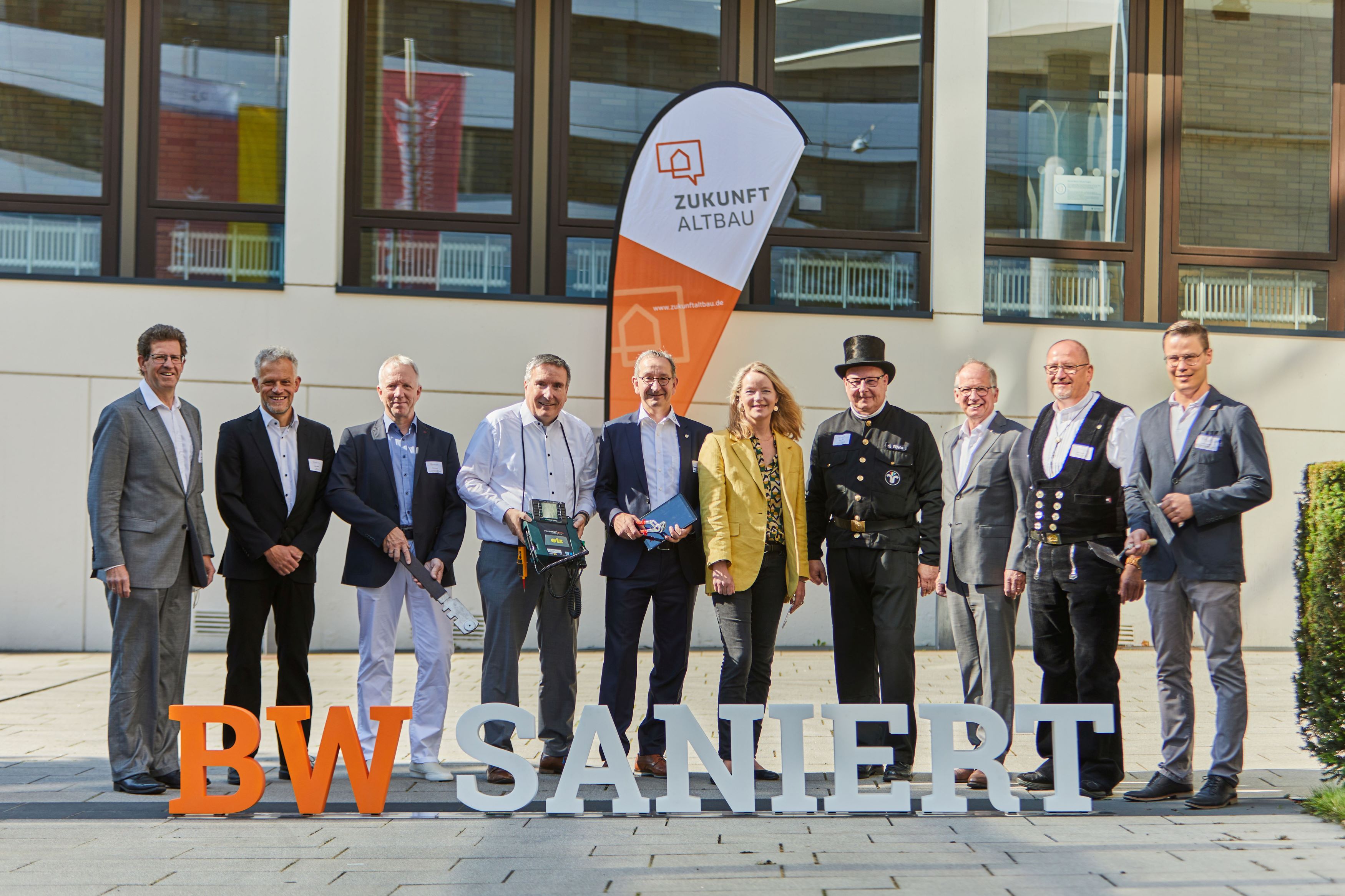 Bild zeigt zehn Personen hinter dem Schild "BW saniert", die in die Kamera lächeln. Die Personen besuchen den Energietag der Klimagewerke.
