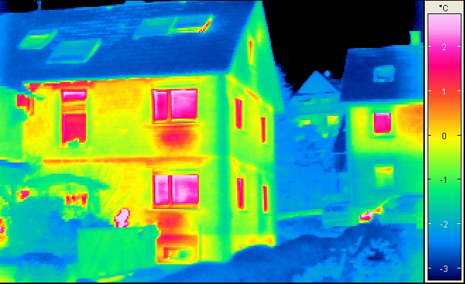 Bild zeigt eine Thermographieaufnahme eines Hauses, das mit einer Wärmebildkamera aufgenommen wurde. Man sieht gelbe, rote, blaue und grüne Bereiche. Sie zeigen die energetische Qualität des Gebäudes an.