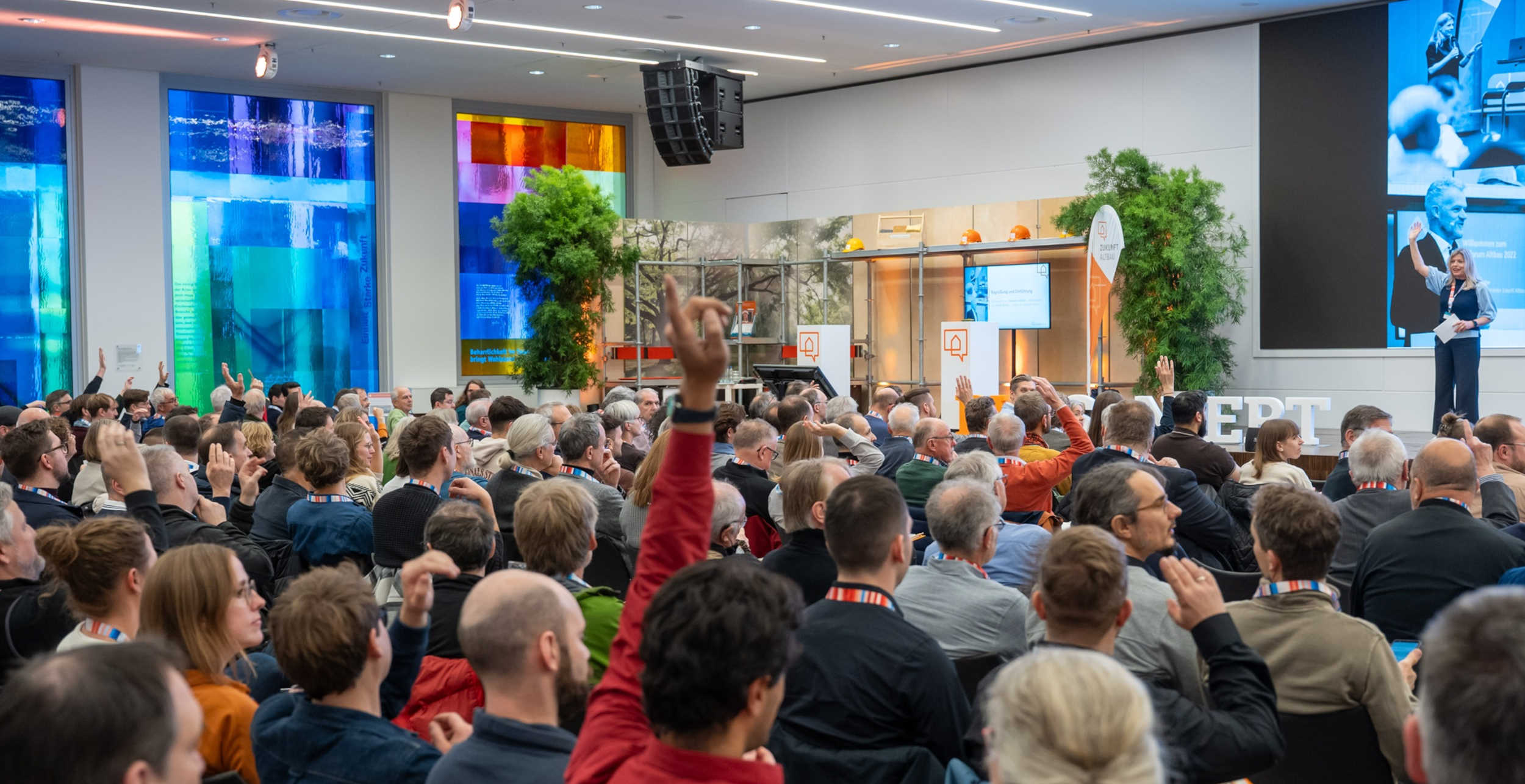 Das Bild zeigt das Publikum einer großen Veranstaltung von hinten im Plenum sitzend. 