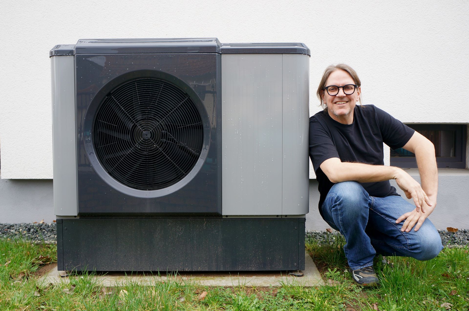 Lohnt sich eine Wärmepumpe für das eigene Haus? Diese und viele andere Informationen gibt es beim „Wegweiser Wärmepumpe“ von Zukunft Altbau mit Carsten Herbert. Auf dem Foto lehnt Carsten Herbert an einer Wärmepumpe.